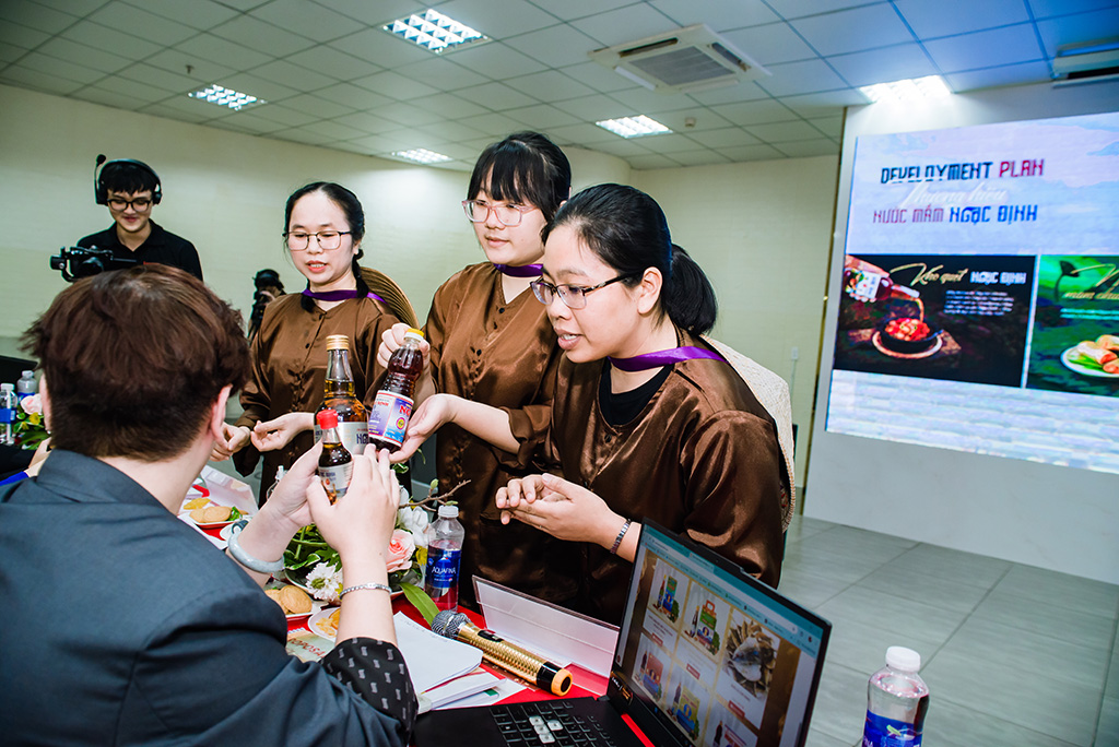 Một nhóm sinh viên trực tiếp pitching ý tưởng truyền thông trước hội đồng giảng viên và đại diện doanh nghiệp.